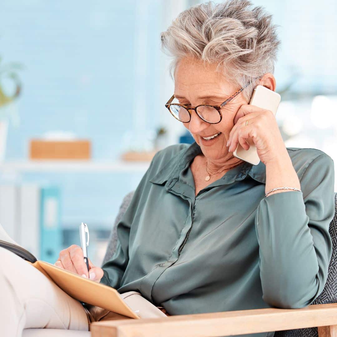 A female lawyer talking on the phone while taking notes in a file.